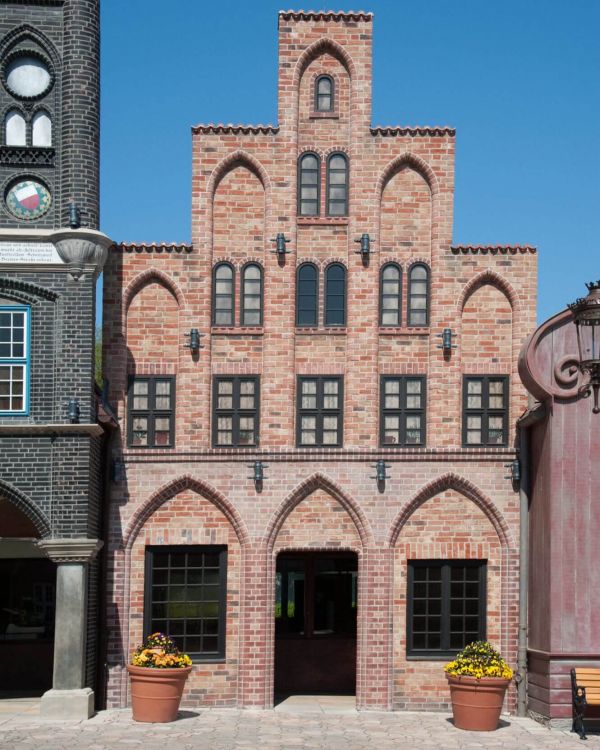 Das Hausbaumhaus aus Rostock. Es ist ein Gebäude mit vielen Bögen und Fenstern mit dunklen Rahmen.