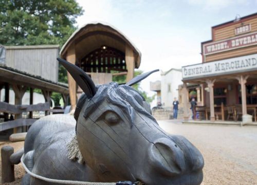 Ein liegendes Pferd aus Holz vor der Postkutsche. Das Pferd hat ein Seil zum Festhalten im Mund.