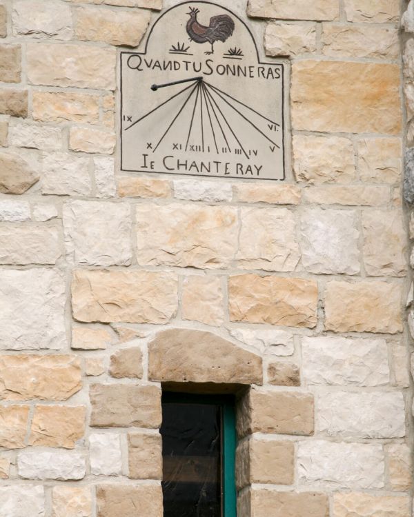 Die Sonnenuhr am Gebäude des Cadran Solaire. Es ist ein Hahn gezeigt und die Uhrzeiten.