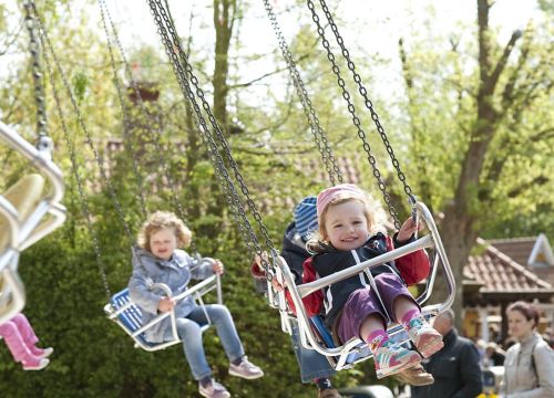 Ein Mädchen und zwei weitere Kinder genießen die Fahrt mit dem Kinder-Kettenkarussell Luftikus.