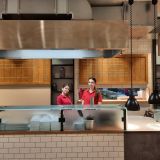 Zwei junge Frauen in HANSA-PARK Arbeitskleidung hinter einem Tresen. Sie lächeln.