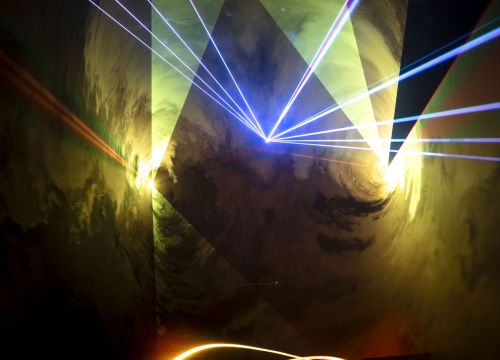 Im Nebel der Lasershow zeigen weiße und orangene Laserstrahlen in die Luft.