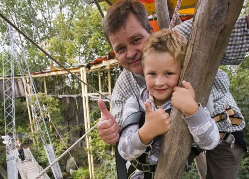 Ein Mann und ein Junge auf dem Hochseilgarten Navajo Trail. Der Mann und der Junge zeigen Daumen.