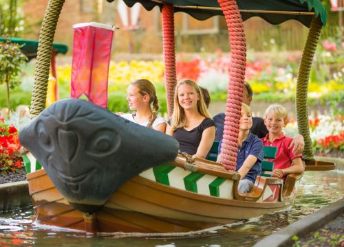 Eine Familie sitzt in dem Boot der Attraktion Blumenmeer-Bootsfahrt. Sie lächeln alle bei der Fahrt.