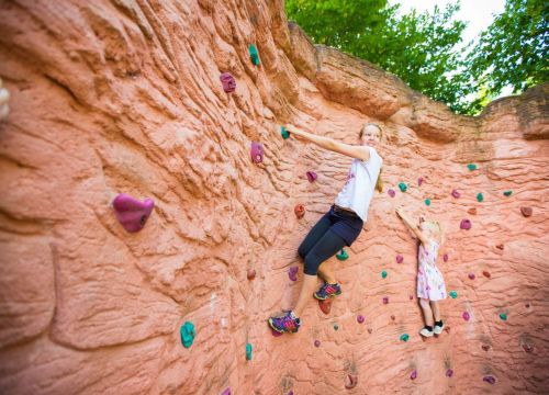 Zwei Mädchen sind an der Kletterwand. Die Große ist etwas höher, als die Kleine.