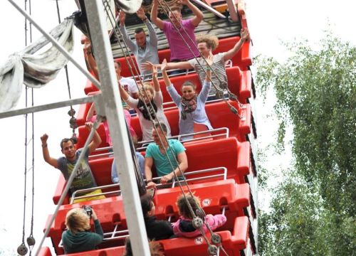 Die Gäste der Attraktion Schiffschaukel genießen die Fahrt mit. Sie nehmen die Arme hoch.