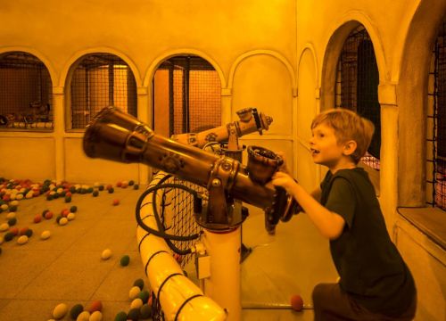 Ein Junge im Spielhaus Fondaco die Tedeschi mit den Händen an der Ballschießanlage.
