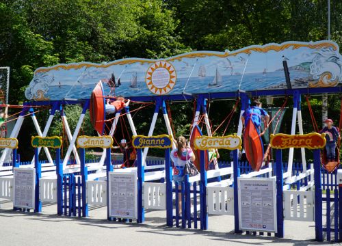 Die Kinder-Schiffschaukel mit Kindern auf den Schiffen. Die einzelnen Schaukeln haben Frauennamen.