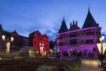 Holstentor des HANSA-PARKs in rosa angestrahlt. Die Speicherhäuser von Hamburg in Rot.