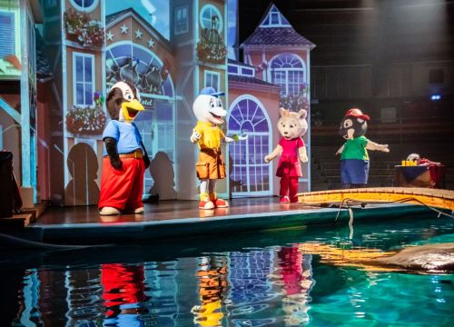 4 HANSA-PARK-Maskottchen stehen auf der Bühne, im Vordergrund ist Wasser zu sehen