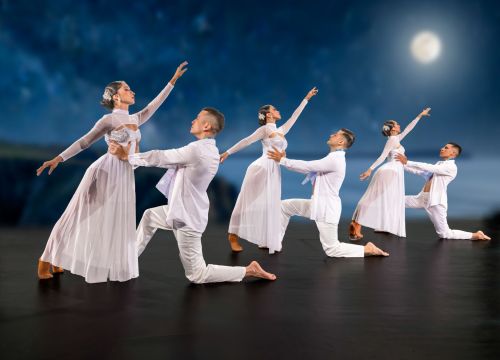 Sechs Balett-Tänzer posieren in weißem Outfit auf der Bühne