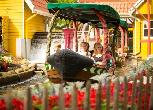 Eine Familie sitzt in dem Boot der Attraktion Blumenmeer-Bootsfahrt und ist gerade eingestiegen.