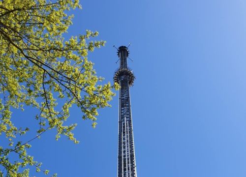 Der HIGHLANDER im Zentrum. Die Gondel ist weit oben beim Turm. Ein Baum im linken Drittel zu sehen.