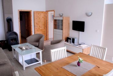 Esstisch, Couch mit zwei Sesseln, einen Couchtisch, ein Schrank, Fernseher und ein Kamin.