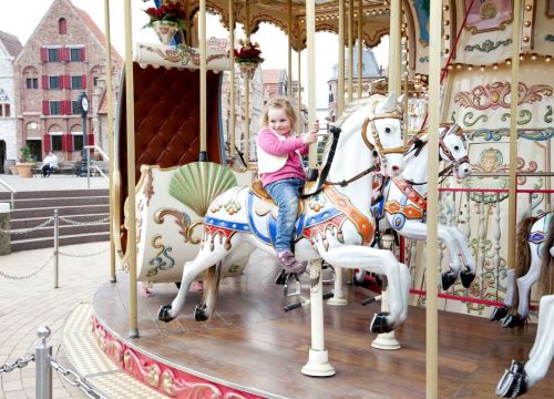 Ein Mädchen sitzt einem Pferd. Eine Kutsche und weitere Figuren sind auf dem HANSE-Karussell.