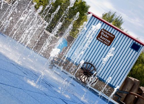 Die sprudelnden Wasserfontänen des Wasserspielplatz Super Splash vor dem Umkleidewagen.