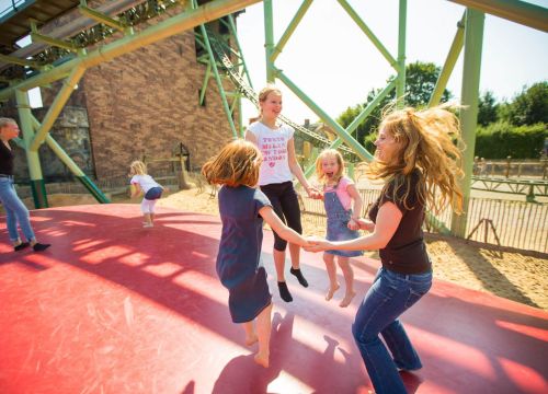 Kinder sind auf dem Hüpfberg. Vier Mädchen hüpfen und halten sich fest. Zwei Mädchen sind hinten.