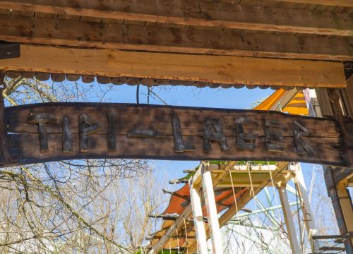Ein Schild auf dem Tipi-Lager steht. Im Hintergrund ist der Hochseilgarten Navajo Trail.