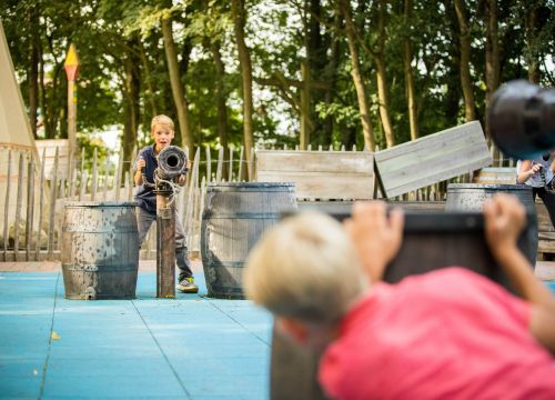 Zwei Jungs stehen sich gegenüber. Einer an der Wasserkanone und ein anderer versteckt sich.