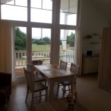 Ein Tisch mit vier Stühlen steht vor einer schmalen Fensterfront. Hintergrund: kleine Küchenzeile.