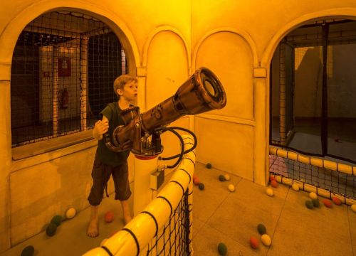 Ein Junge im Spielhaus Fondaco die Tedeschi mit den Händen an der Ballschießanlage von vorne.