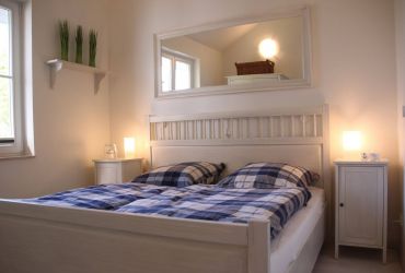 Ein Doppelbett mit Nachtisch und einem Spiegel über dem Bett.