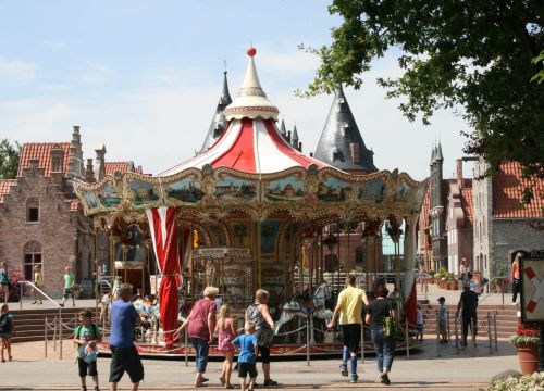 Ein Mädchen sitzt einem Pferd. Eine Kutsche und weitere Figuren sind auf dem HANSE-Karussell.