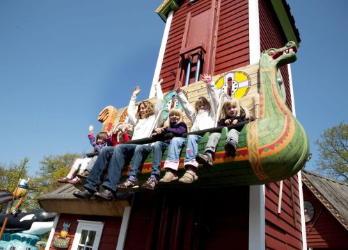 In den Sitzen von Elins Luftreise sitzen Kinder. Einige heben die Arme und schauen runter.
