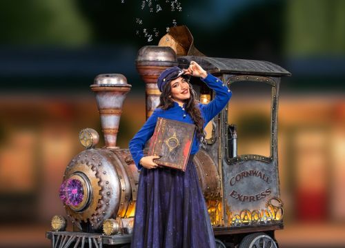 Künstlerin posiert vor der Lok des Cornwall Expresses