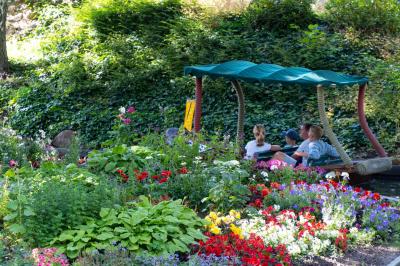 Ein Boot mit Gästen fährt durch die bunte Blumenpracht der Attraktion Blumenmeer-Bootsfahrt.