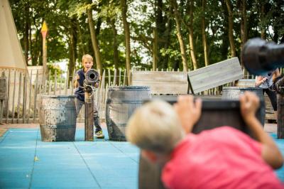 Zwei Jungs stehen sich gegenüber. Einer an der Wasserkanone und ein anderer versteckt sich.