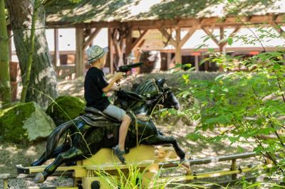 Ein Junge reitet mit einem schwarzen Plastikpferd über die Bahn der Attraktion Pony-Post.