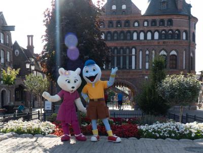 Die Maskottchen Flipsi und Emmi steht vor dem Holstentor. Sie freue sich auf das Meet and Great.