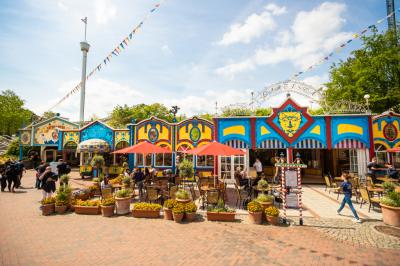 Auf der Terrasse vom Restaurant L’Artista stehen rote Sonnenschirme, Stühlen und Tischen.