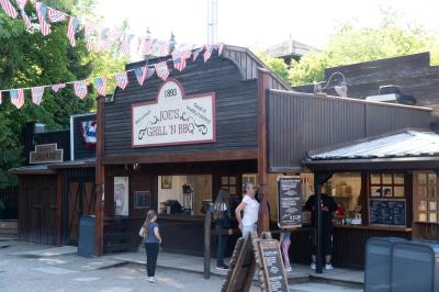 Ein paar Gäste stehen beim Kiosk Joes’s Grill N BBQ. Eine Frau ließt die Karte. Ein Mädchen wartet.