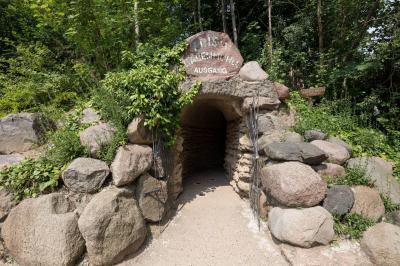 Der Ausgang der Bärenhöhle. Aus bewachsenen Steinen kommt man durch ein geöffnetes Tor nach draußen.