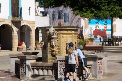 Zwei Kinder vor dem sprechenden Brunnen. Sie schauen sich den Brunnen genauer an.