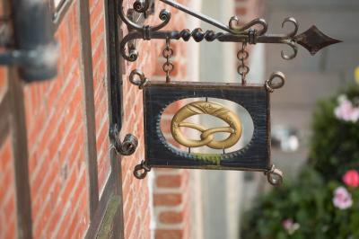 Ein Schild mit einer goldenen Brezel. Diese hängt an den Arkaden auf den Vorplatz.