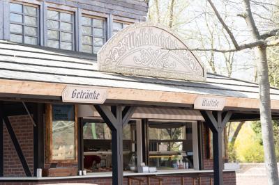 Das Gebäude des Kiosks Waffelbackstube von außen. Zwei Schilder weisen auf Waffeln und Getränk hin.