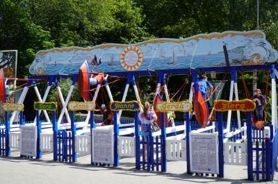 Die Kinder-Schiffschaukel mit Kindern auf den Schiffen. Die einzelnen Schaukeln haben Frauennamen.