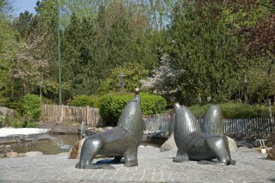 Vier Seelöwen aus Bronze vor einem Wasserspiel. Einer der Seelöwen hat einen Ball auf der Nase.