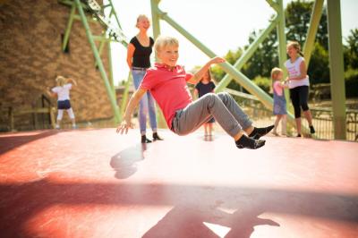 Kinder sind auf dem Hüpfberg. Ein Junge schwebt ist in der Luft. Im Hintergrund sind andere Kinder.