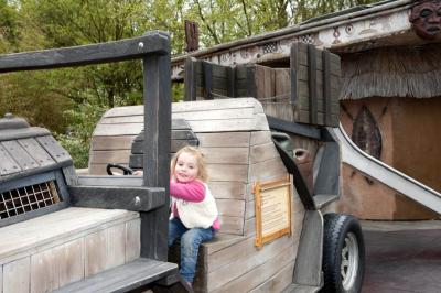 Auf dem Dschungel Jeep aus Holz sitzt ein Mädchen. Es hält sich am Lenkrad fest.