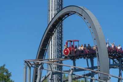 Der Zug des Royal Scotsman fährt unter dem Looping der Bahn Nessi durch. Die Gäste heben die Hände.