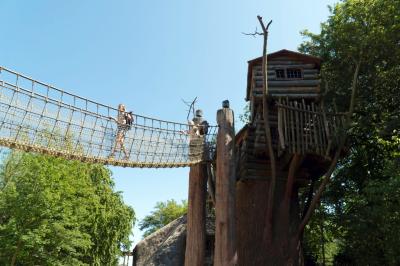 Die Apachen Lodge und Hängebrücke von unten. Zwei Mädchen laufen über die Hängebrücke.