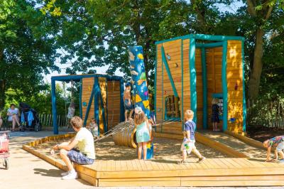 Ganz viele Kinder auf dem Inklusionspielplatz Patio del Mar. Ein Mann sitzt und wartet.
