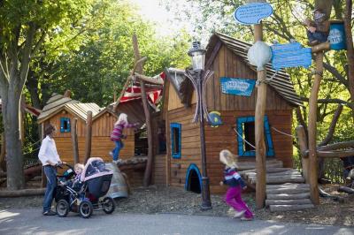 Die Kletterhäuser des Niedrigseilgartens. Kinder rennen, klettern und toben. Eine Mutter beobachtet.