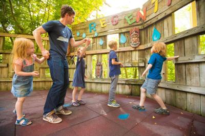 Ein Erwachsener und vier Kinder sind beim Regentanz. Aus einem Loch der Wand kommt ein Wasserstrahl.