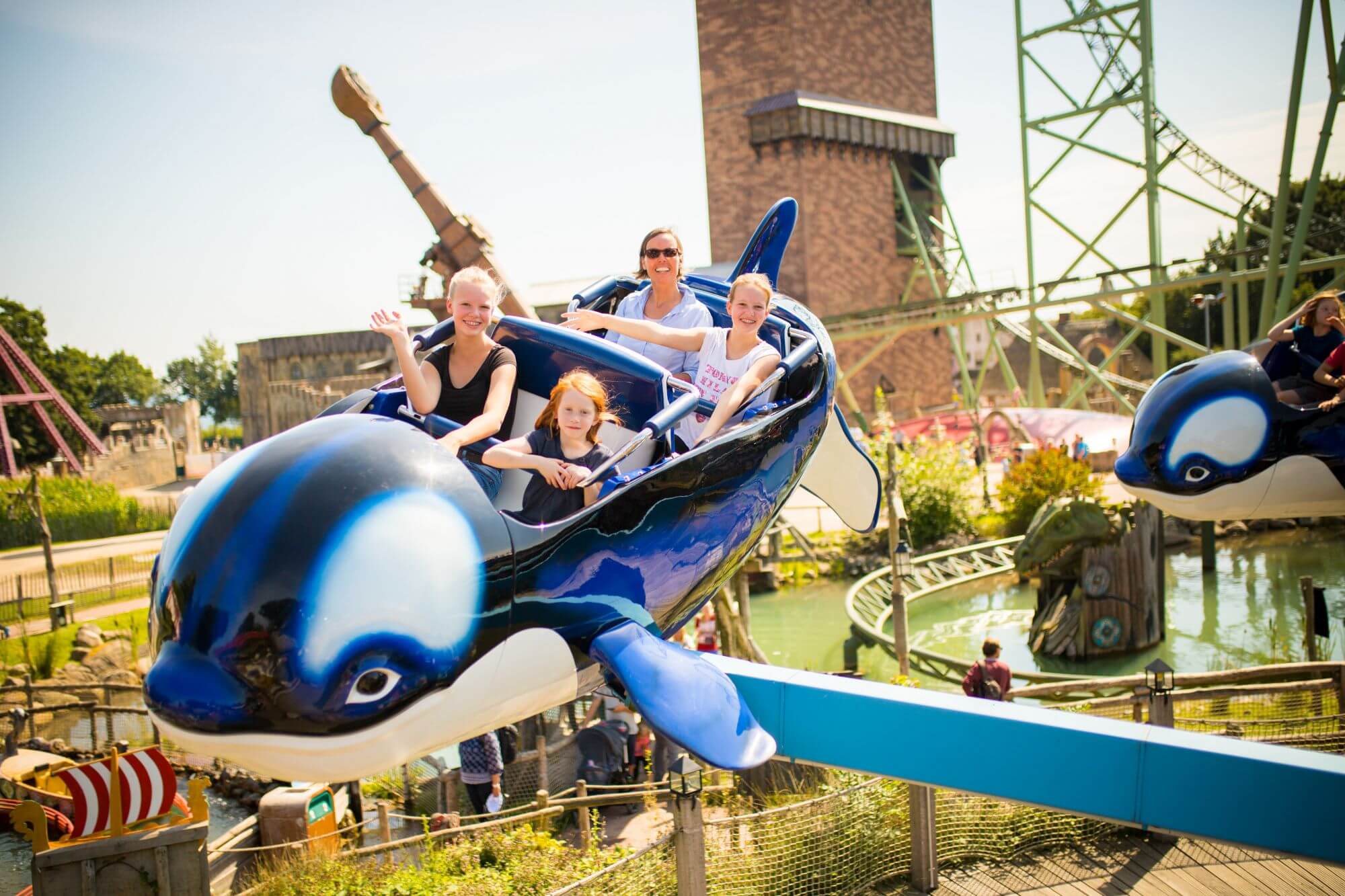 Ein Orca der Attraktion Flying Orca mit vier Gästen drin. Der Orca ist oben in der Luft.