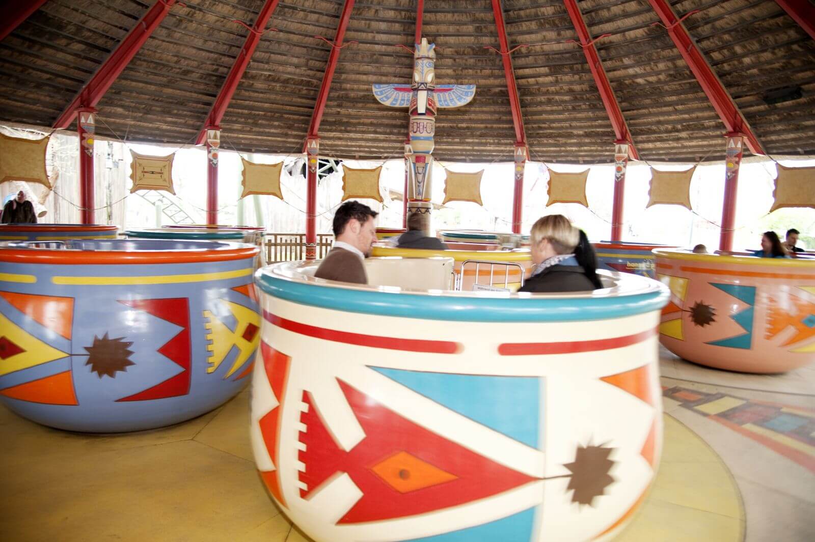 In den Tassen der Attraktion Pow Wow sitzen Gäste. Die Tassen drehen sich.